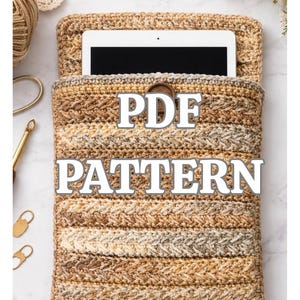 Puede incluir: Una funda de tableta de ganchillo en tonos marrón, beige y crema, con un patrón de puntada texturizada. El texto "PDF PATTERN" se muestra en la parte delantera. La funda está abierta en la parte superior, revelando una tableta.