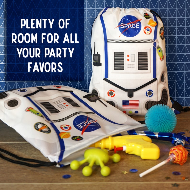 May include: Two white drawstring bags with a space-themed design. The bags have a zipper, a NASA logo, and the word "SPACE" printed on them. The bags are filled with party favors, including a water gun, a toy alien, a lollipop, and a blue spiky ball.