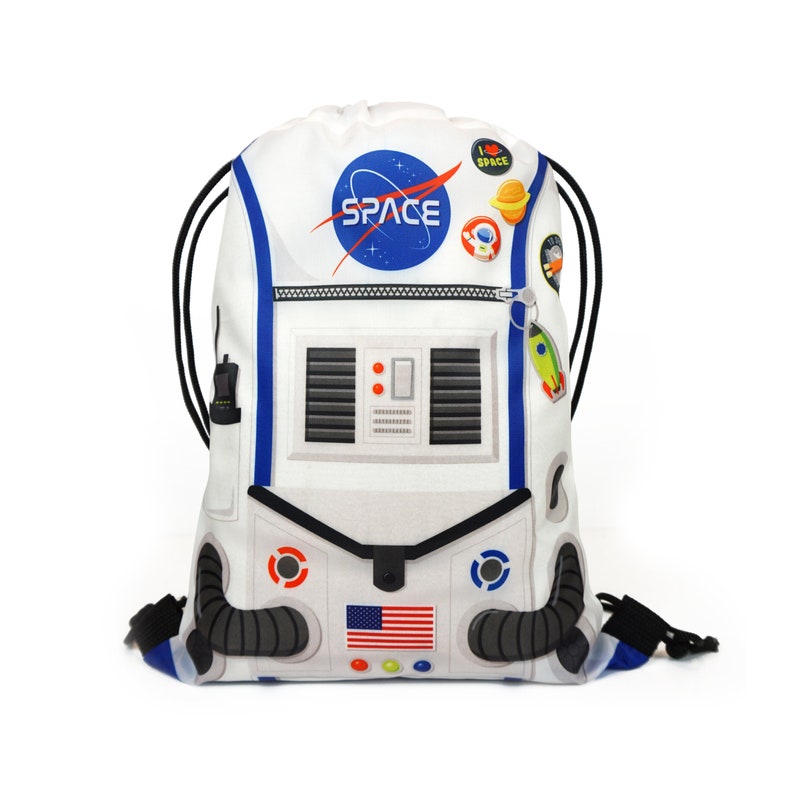 May include: White drawstring bag with an astronaut design. The bag features a blue and white NASA logo, an American flag, and the word "SPACE" in blue letters.