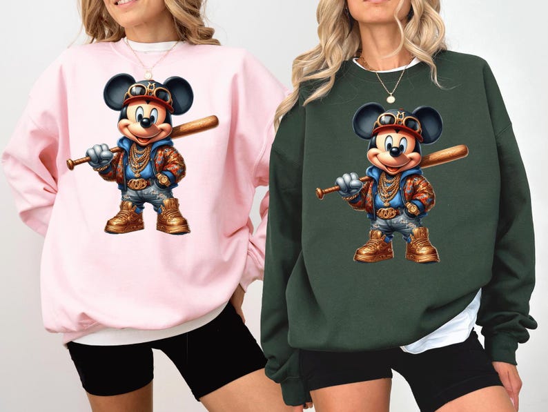 May include: Two pink and green sweatshirts with a cartoon image of Mickey Mouse wearing a gold chain and holding a baseball bat. The Mickey Mouse image is in a graffiti style.