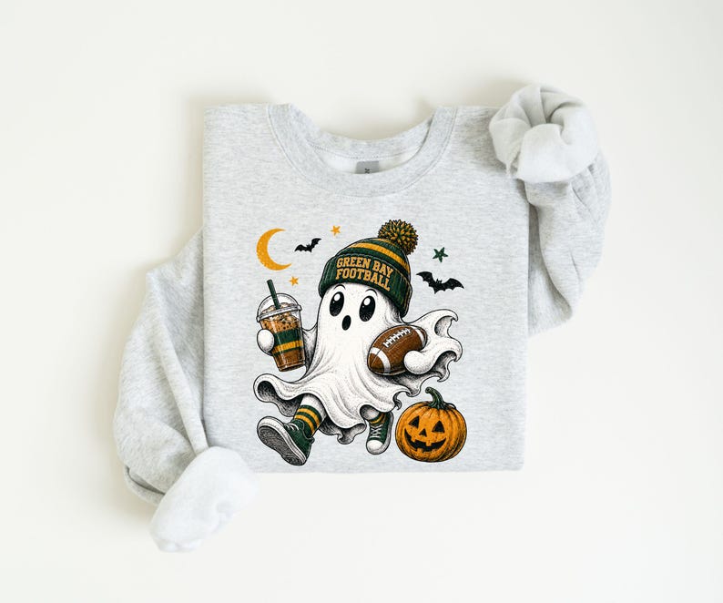 A gray sweatshirt with a graphic design depicting a ghost character wearing a football hat and holding a football, along with a pumpkin and a cup of coffee.