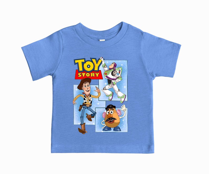 May include: A light blue short-sleeve t-shirt featuring a graphic print of the Toy Story logo and characters Woody, Buzz Lightyear, and Mr. Potato Head. The design is set against a light blue background with white star accents and rectangular frames.