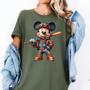 May include: A green t-shirt with a cartoon image of Mickey Mouse wearing a gold chain, a baseball cap, and holding a baseball bat.
