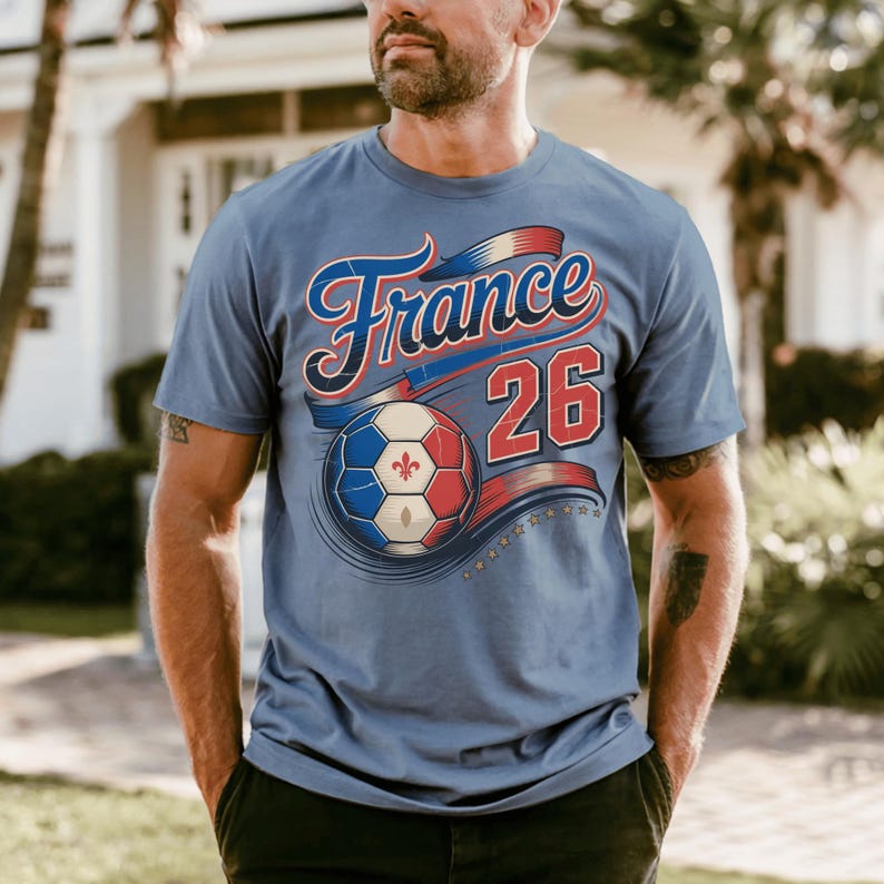 K&ouml;nnte beinhalten: Hellblaues T-Shirt mit dem Wort "France" in roter und blauer Schrift sowie der Nummer "26". Unter dem Text befindet sich ein Fu&szlig;ball in den Farben der franz&ouml;sischen Flagge. Das T-Shirt hat kurze &Auml;rmel.