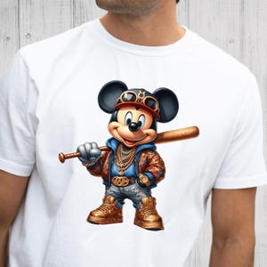 May include: White t-shirt with a cartoon image of Mickey Mouse wearing a baseball cap, sunglasses, and a gold chain. He is holding a baseball bat and wearing blue jeans and gold sneakers.