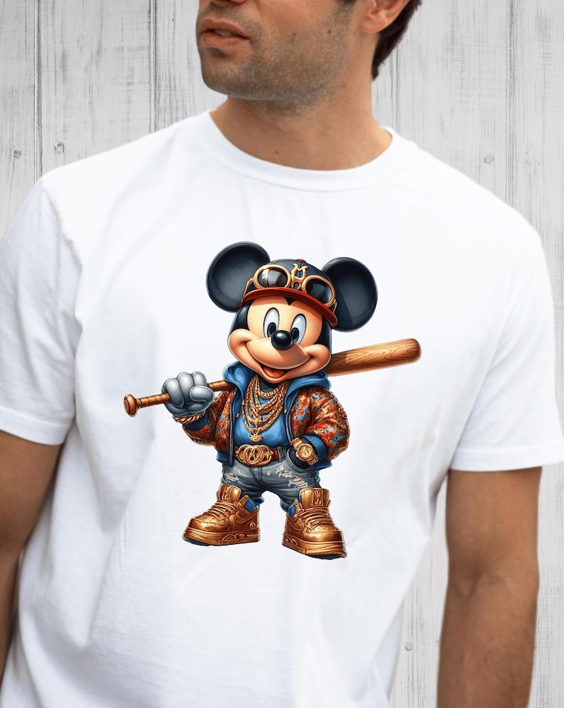 May include: White t-shirt with a cartoon image of Mickey Mouse wearing a baseball cap, sunglasses, and a gold chain. He is holding a baseball bat and wearing blue jeans and gold sneakers.