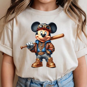 May include: A white t-shirt with a cartoon image of Mickey Mouse wearing a gold chain, sunglasses, and a baseball cap. Mickey is holding a baseball bat and is wearing blue jeans and gold sneakers.