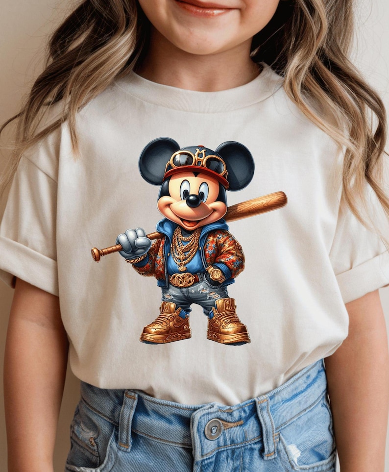 May include: A white t-shirt with a cartoon image of Mickey Mouse wearing a gold chain, sunglasses, and a baseball cap. Mickey is holding a baseball bat and is wearing blue jeans and gold sneakers.