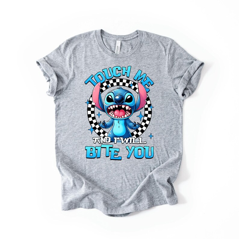 May include: A gray t-shirt featuring a cartoon character with blue fur, large ears, and an open mouth. The text "TOUCH ME AND I WILL BITE YOU" is printed in blue above and below the character.