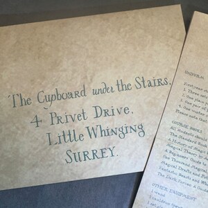 K&ouml;nnte beinhalten: Ein brauner Papierumschlag mit der Adresse "The Cupboard under the Stairs, 4 Privet Drive, Little Whinging SURREY." in Kursivschrift. Der Umschlag listet auch die Uniform- und Kursbuch-Anforderungen f&uuml;r Erstsemester auf.