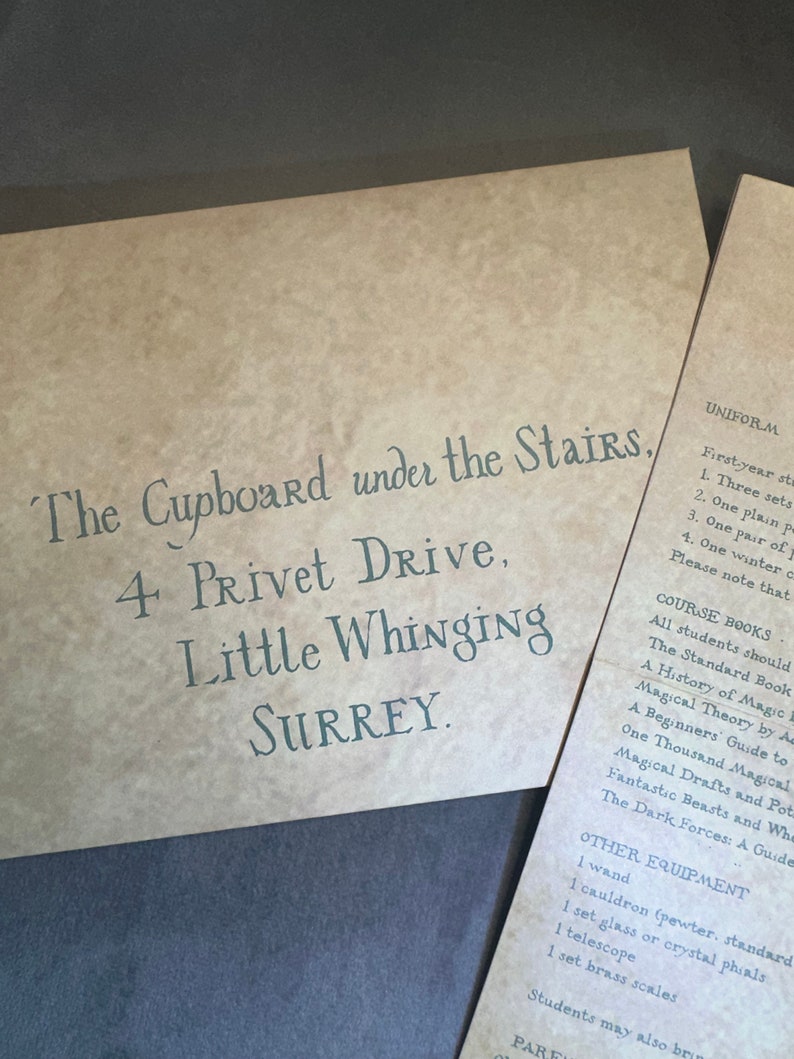 K&ouml;nnte beinhalten: Ein brauner Papierumschlag mit der Adresse "The Cupboard under the Stairs, 4 Privet Drive, Little Whinging SURREY." in Kursivschrift. Der Umschlag listet auch die Uniform- und Kursbuch-Anforderungen f&uuml;r Erstsemester auf.