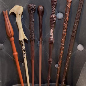 May include: Six wooden wands with different designs and colors. The wands are made of wood and have intricate carvings. The wands are all different lengths and have different tips.