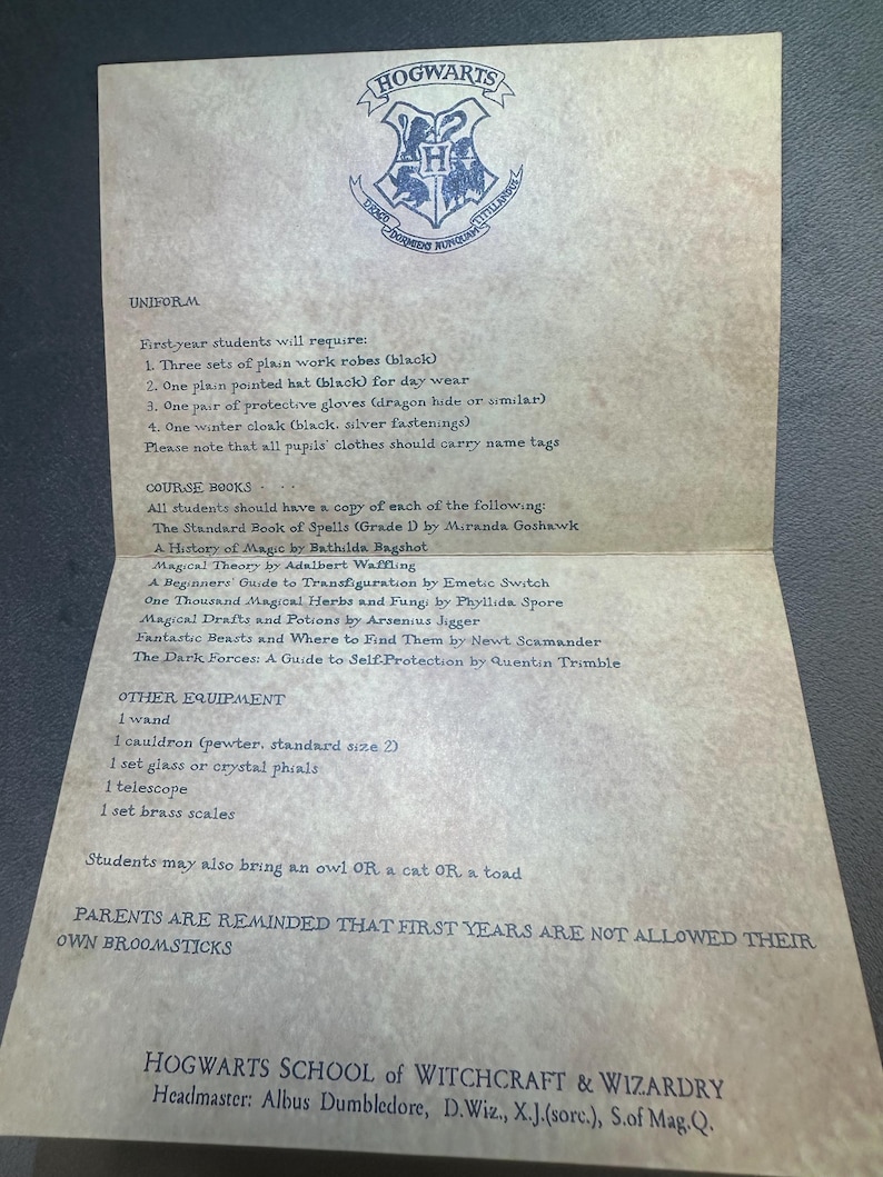 K&ouml;nnte beinhalten: Ein Hogwarts-Schule f&uuml;r Hexerei und Zauberei-Zulassungsschreiben mit einer Liste der erforderlichen Uniformartikel, Lehrb&uuml;cher und anderer Ausr&uuml;stung f&uuml;r Erstsemester. Der Brief ist auf Pergamentpapier mit einem Hogwarts-Wappen oben gedruckt.