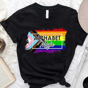 May include: Black t-shirt with a rainbow flag design and the text "Alphabet Mafia" in a white box.