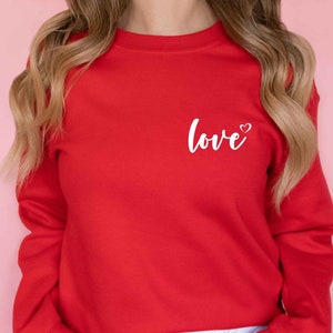 May include: A red sweatshirt with the word "love" and a small heart printed on the front.