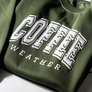 May include: A green sweatshirt with white lettering that reads "COFFEE WEATHER".