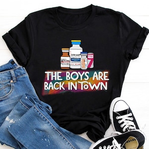 May include: Black t-shirt with a graphic of several bottles of medication and the text "The Boys Are Back In Town" in rainbow colors.