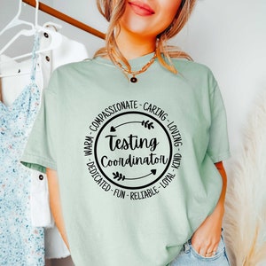 May include: A light green t-shirt with a black circle graphic that says "Testing Coordinator" surrounded by positive adjectives.
