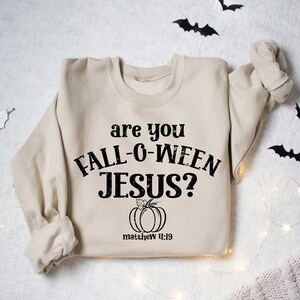 May include: A beige sweatshirt with the text "are you fall-o-ween jesus?" and a pumpkin graphic. The text "matthew 4:19" is below the pumpkin.