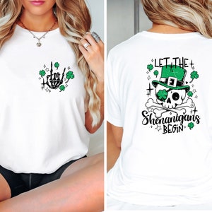 May include: White t-shirt with a green shamrock and skeleton hand graphic on the front and a green skull wearing a leprechaun hat with the text "Let the Shenanigans Begin" on the back.