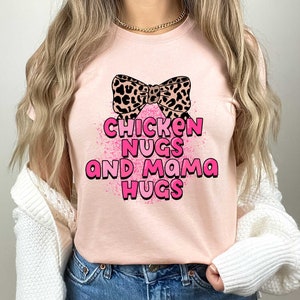 May include: A pink t-shirt with a leopard print bow and the text "Chicken Nugs and Mama Hugs" in pink letters.