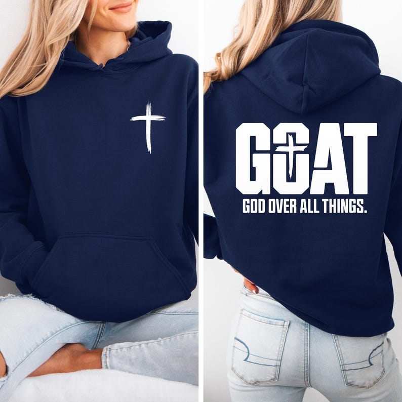 Pode incluir: Moletom azul marinho com uma cruz branca na frente e a palavra "GOAT" com uma cruz no "O" nas costas. O texto "GOD OVER ALL THINGS" est&aacute; abaixo da palavra "GOAT". O moletom tem um bolso frontal e um capuz.