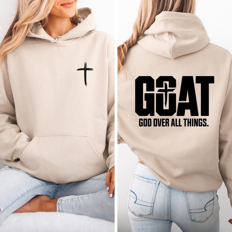 Pode incluir: Um moletom bege com bolso frontal e capuz. Uma cruz preta &eacute; impressa na frente. A parte de tr&aacute;s do moletom apresenta a palavra "GOAT" com uma cruz e o texto "GOD OVER ALL THINGS."