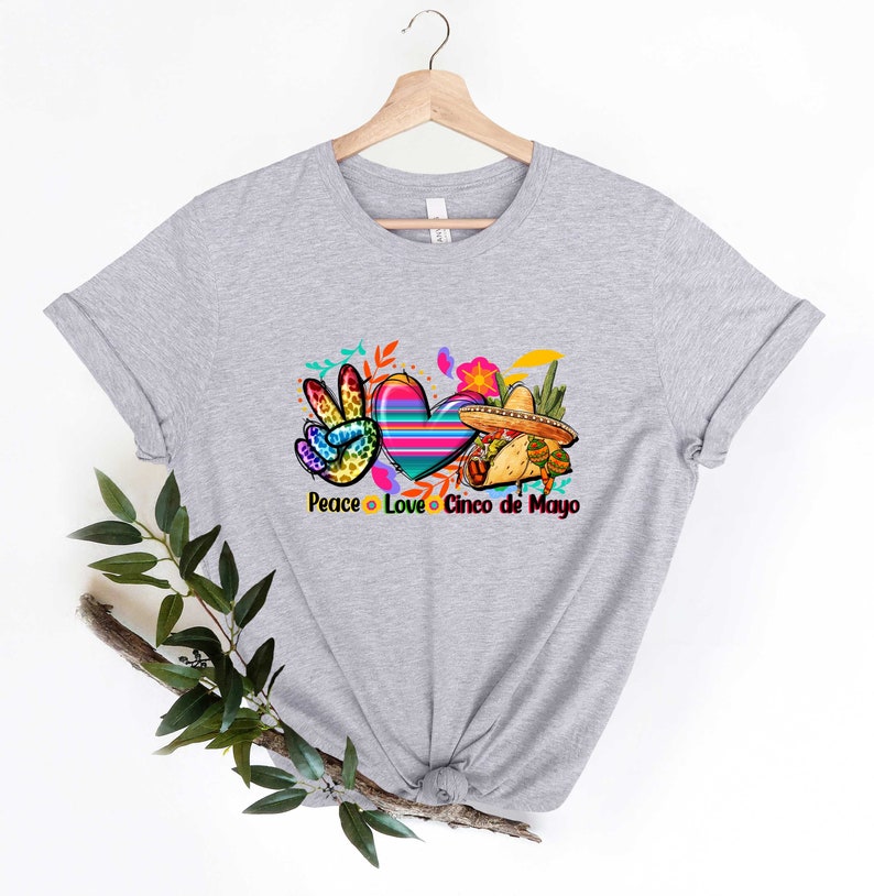 Puede incluir: Camiseta gris con un signo de paz, un coraz&oacute;n y un sombrero con el texto "Peace Love Cinco de Mayo".