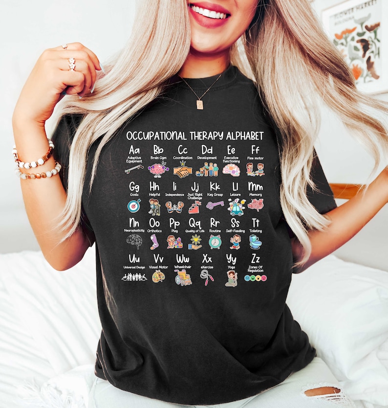 May include: Black t-shirt with a white graphic of an occupational therapy alphabet. Each letter is paired with an image and a word related to occupational therapy. For example, "Aa" is paired with "Adaptive Equipment" and an image of a wheelchair.