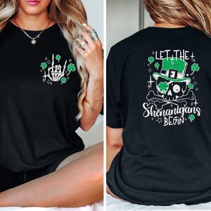 May include: Black t-shirt with a green shamrock and skeleton hand graphic on the front and a green skull wearing a leprechaun hat with the text "Let the Shenanigans Begin" on the back.