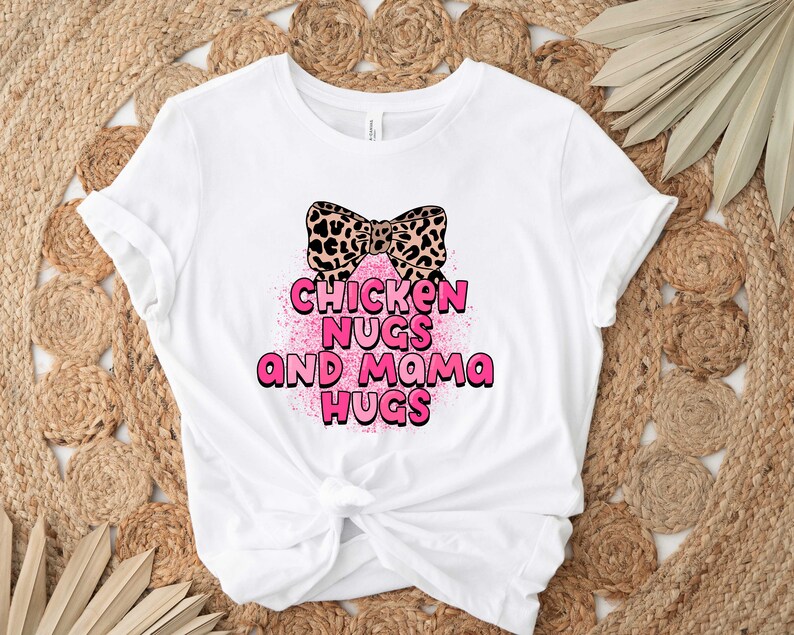 May include: White t-shirt with a pink bow and the text "Chicken Nugs and Mama Hugs" in pink.