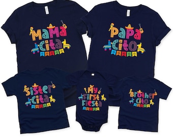 May include: A set of five navy blue t-shirts with colorful text and graphics. The shirts feature the phrases "Mama Cita", "Papa Cito", "Sister Cita", "My First Fiesta", and "Brother Cito".