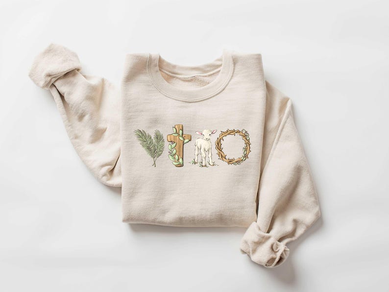 May include: A beige sweatshirt with a graphic design of a cross, a lamb, and a crown of thorns. The design is in shades of brown, green, and white.