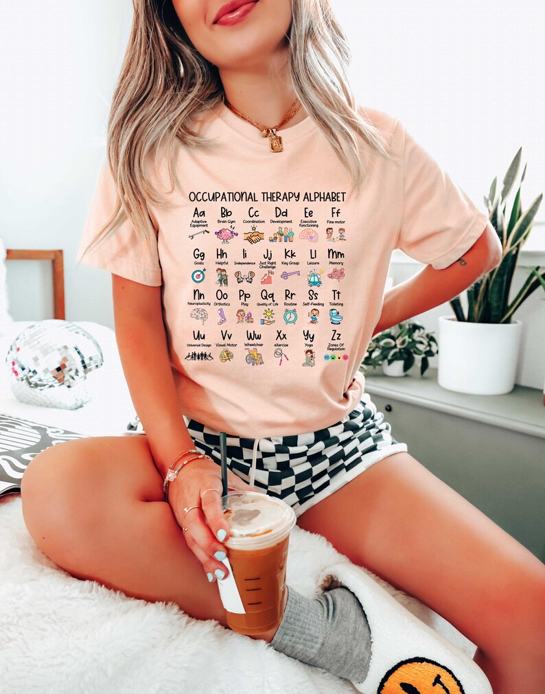 May include: A pink t-shirt with the text "Occupational Therapy Alphabet" and a grid of letters with corresponding icons and descriptions. The letters are A through Z, and the icons represent different aspects of occupational therapy.