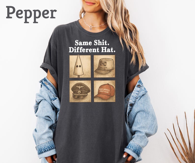 Peut inclure: T-shirt gris fonc&eacute; avec le texte "Same Shit. Different Hat." et quatre illustrations de chapeaux. Les chapeaux comprennent une cagoule blanche pointue, un chapeau militaire, un chapeau marron avec un &eacute;cusson et un chapeau rouge "Make America Great Again".