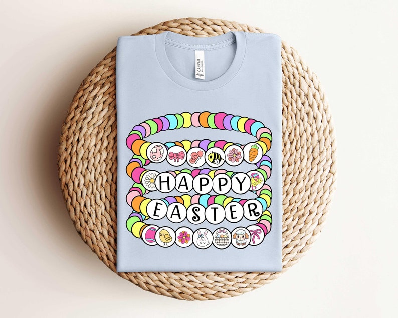 May include: Light blue t-shirt with a colorful beaded design that spells out "Happy Easter". The beads are decorated with small Easter-themed images.