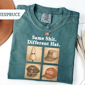 Peut inclure: T-shirt Comfort Colors bleu sarcelle avec le texte "Same Shit. Different Hat." et quatre illustrations de chapeaux. Un collier dor&eacute; et un chapeau marron sont &eacute;galement visibles.