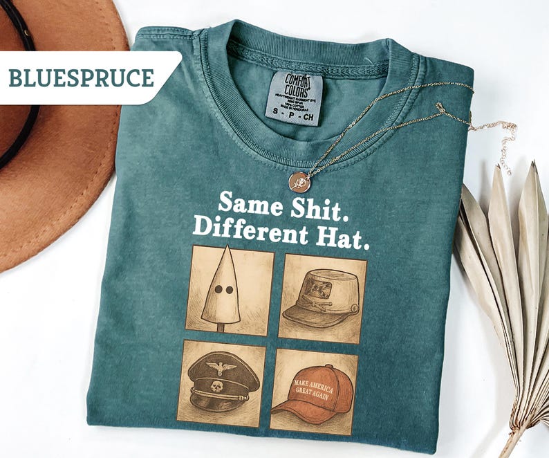 Peut inclure: T-shirt Comfort Colors bleu sarcelle avec le texte "Same Shit. Different Hat." et quatre illustrations de chapeaux. Un collier dor&eacute; et un chapeau marron sont &eacute;galement visibles.