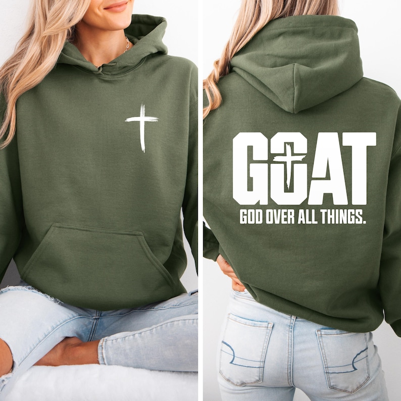 Pode incluir: Moletom verde-oliva com uma cruz branca na frente e o texto "GOAT GOD OVER ALL THINGS" nas costas. Possui capuz e bolso frontal. Feito de um material macio.