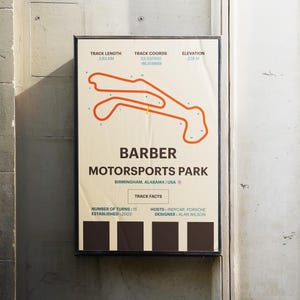 May include: A poster with a map of the Barber Motorsports Park racetrack in Birmingham, Alabama. The track is outlined in orange and the poster includes information about the track, including its length, coordinates, elevation, number of turns, hosts, and designer.