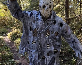 May include: A costume featuring a weathered, off-white hockey mask with red markings, a distressed grey button-down shirt with numerous tears, matching tattered trousers, a heavy metal chain draped over the chest, and a dark, blood-stained machete.