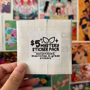 Puede incluir: Un paquete de pegatinas blanco con el texto "$5 MYSTERY STICKER PACK" y las palabras "discontinued, misprinted, B-grade stickers". El paquete de pegatinas se sostiene en una mano, con varias impresiones artísticas coloridas en el fondo.