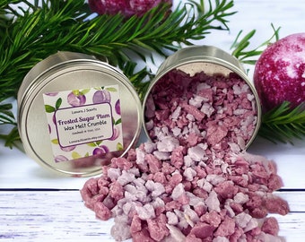 May include: A silver tin filled with pink and purple wax melt crumbles. The tin has a label that reads "Frosted Sugar Plum Wax Melt Crumble" and "Lonora J Scents".