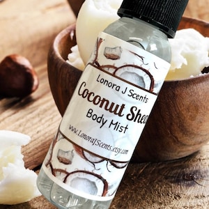 May include: A clear glass bottle with a black spray top and a white label. The label has a watercolor design of coconuts and the text "Lonora J Scents Coconut Shea Body Mist www.LonoraJScents.etsy.com".