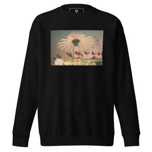 May include: Black sweatshirt featuring a vintage-style image of a carnival swing ride with bright lights. The image includes the text "HAVE WE BEEN HERE BEFORE?" in a yellow font. The sweatshirt has a crew neck and long sleeves.