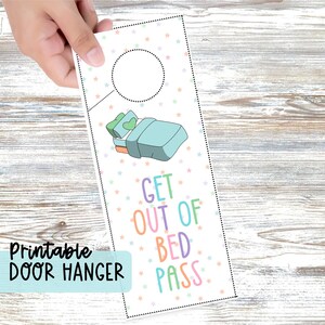 May include: A rectangular door hanger with a white background featuring a pattern of small pastel-colored stars. The design includes a cartoon illustration of a bed and the text GET OUT OF BED PASS in colorful letters, with a circular cutout at the top.