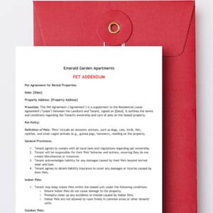 May include: A white document titled Emerald Garden Apartments PET ADDENDUM with black text detailing a pet agreement for rental properties, placed in front of a red envelope with a circular flap and a gold-colored metal eyelet closure.
