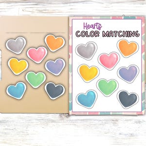 May include: A printable activity for kids featuring a color matching game with hearts in various colors. The title of the game is "Hearts Color Matching".