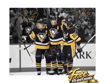 Puede incluir: Una fotografía en blanco y negro de tres jugadores de hockey con camisetas de los Pittsburgh Penguins, cada uno con casco y un palo de hockey. La imagen incluye firmas de color dorado superpuestas sobre los jugadores y el hielo.