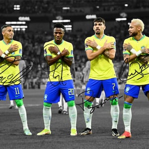 May include: Four soccer players in yellow and blue uniforms stand on a field. They are all wearing the same uniform with different numbers. The players are all looking at the camera. The background is blurred.